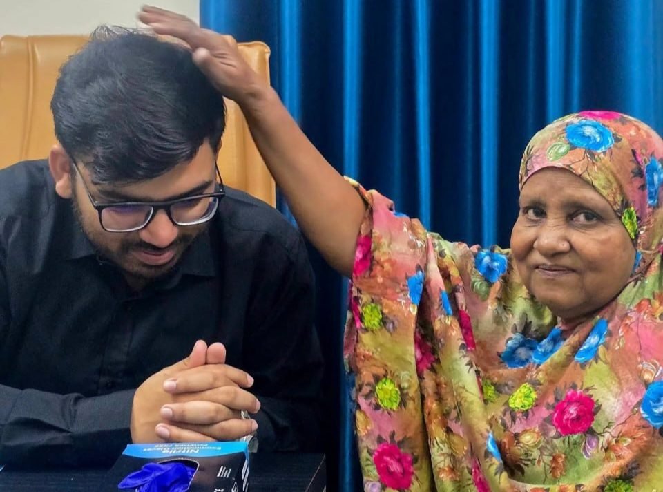 An elderly patient offering prayers with her hand on Dr. Khaled Hasan Milu's head